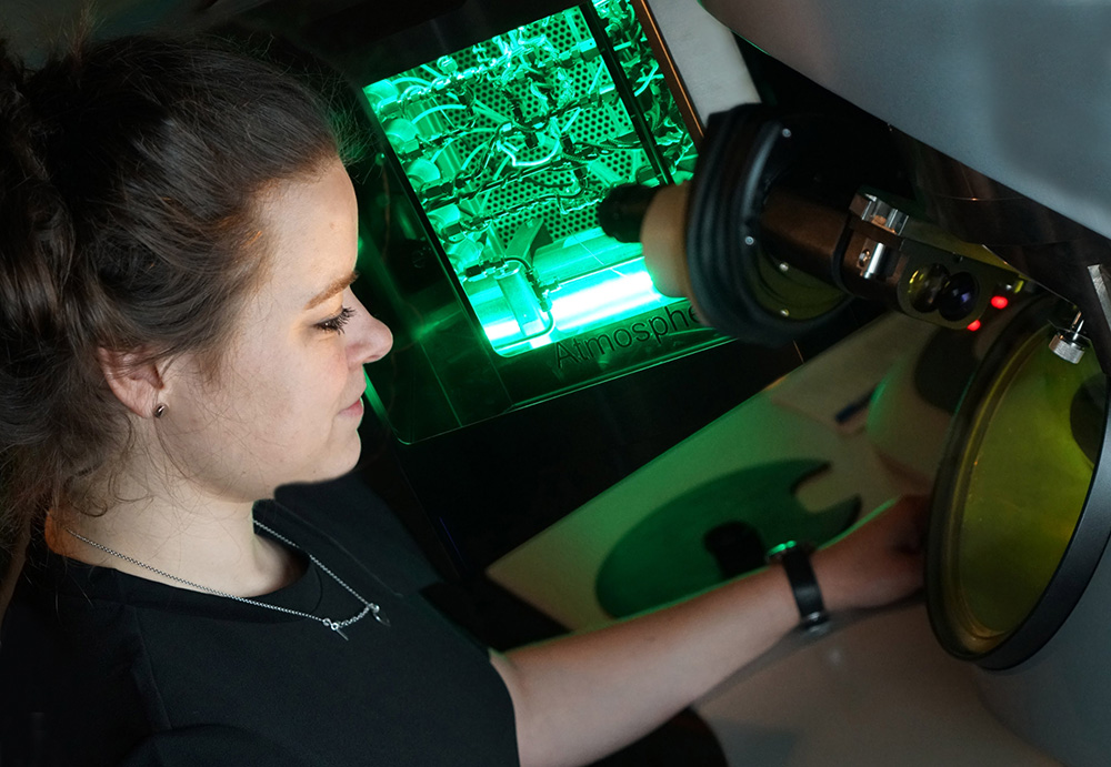 Researcher working in the lab in front of a microscope at UiO. Photo